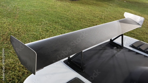 Foto High angle close up of large matte black racing spoiler wing on white sports car