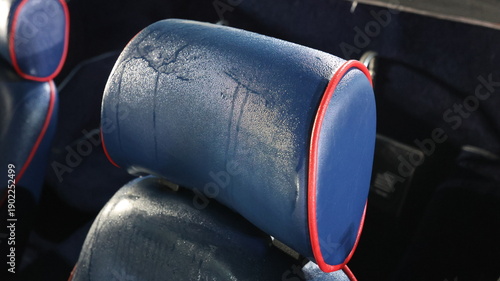 Fotografía Close up of wet blue vintage car seat headrest with red piping covered in dew