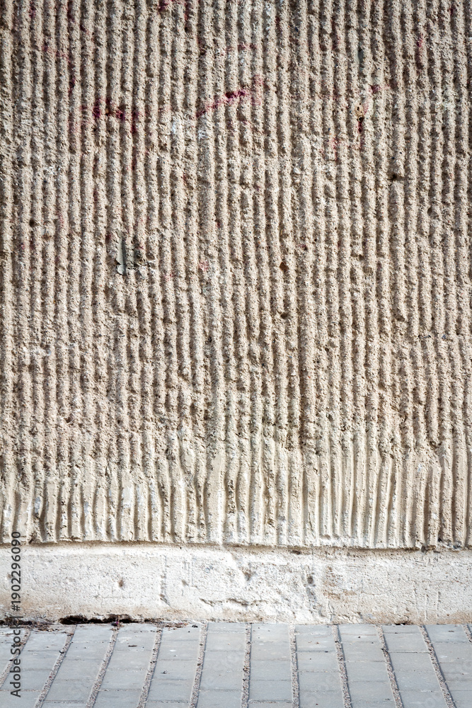 Naklejka premium Gray lined stucco street wall and a pavement