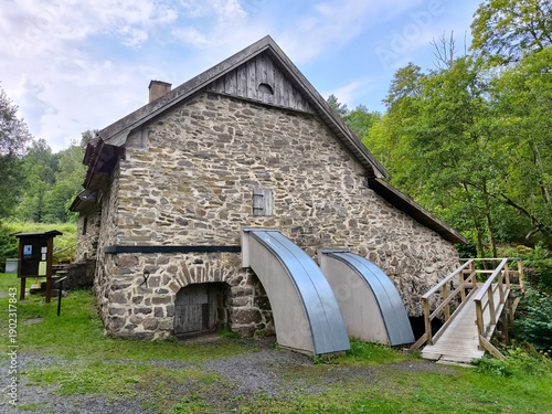 Rasmus Kvarn, Sweden - August 30th 2024: View of Rasmus Kvarn, a traditional wooden water mill with a red tiled roof, wooden footbridge and surrounding forest landscape in Sweden