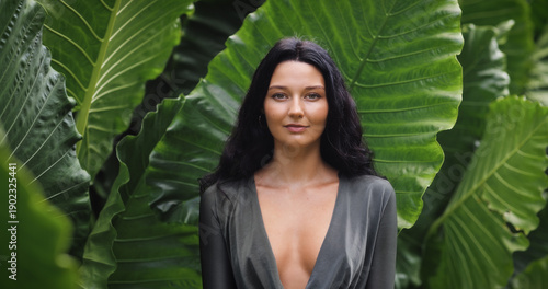 Confident Woman Standing Against Giant Tropical Leaves in Jungle Setting
