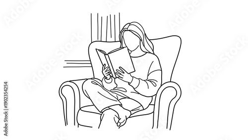 A woman sits comfortably in an armchair, engrossed in reading a book with a thoughtful expression.