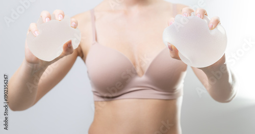 Canvas Print Female adult squeezes silicone breast implants in hands for cosmetic surgery con