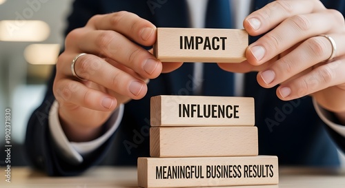 Businessman stacking wooden blocks labeled impact influence and meaningful business results demonstrating strategic management concepts clearly