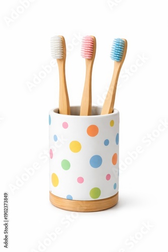 Eco friendly bamboo toothbrushes with colored bristles in white polka dot holder isolated