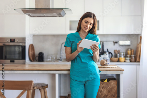 Professional woman in scrubs smiling, using a tablet reflecting modern healthcare and telemedicine concepts.