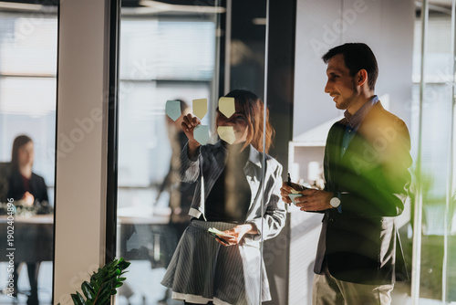Fotografia Two business people collaborate in a glass-walled office