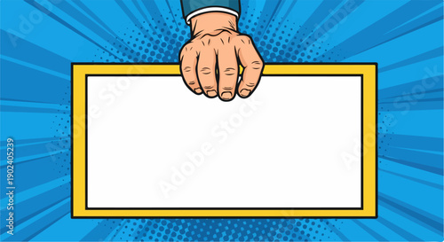 Pop art hand holding a blank yellow frame on a blue comic background.