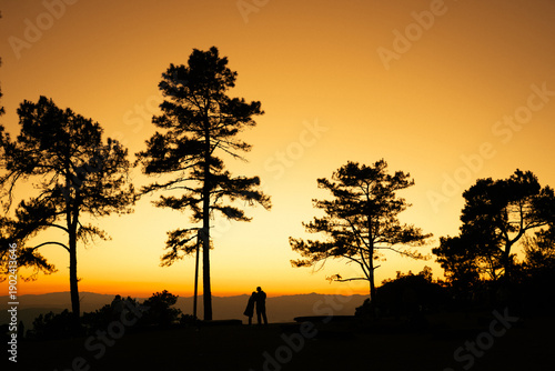 Couple looking beautiful view mountain  trees and warm sunlight peeking over the peaks.