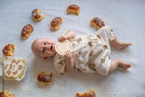 A baby is laying on a table with a bunch of donuts and a few pieces missing