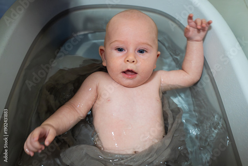 A baby is in a bathtub with water splashing around him