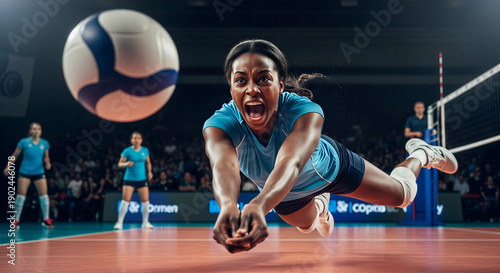 Black female indoor volleyball player diving to save ball in arena