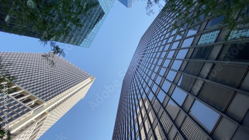 Fotografie Modern urban city skyscrapers reaching towards clear blue sky, low angle view sh