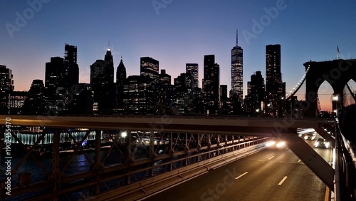 Bild auf Leinwand Brooklyn bridge roadway at night with light trails from moving vehicles and a il
