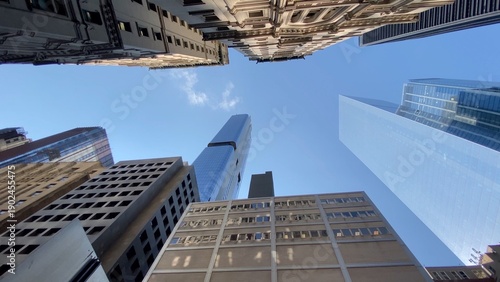 Foto Towering skyscrapers form an urban canyon against a clear blue sky, low-angle vi