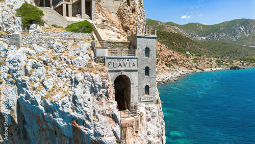 Fotografie The iconic facade of Porto Flavia ore loading terminal carved into the cliffs ab