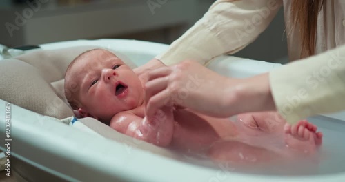 Parent gently bathes newborn baby in specialized infant tub with soft support for comfort and safety. Newborn Baby Bath Time