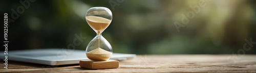 Contemplative vintage hourglass with golden sand passing. concept of time management, deadline and countdown on wooden table