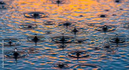 Close-up shot of raindrops creating ripples on a shimmering water surface with an orange glow