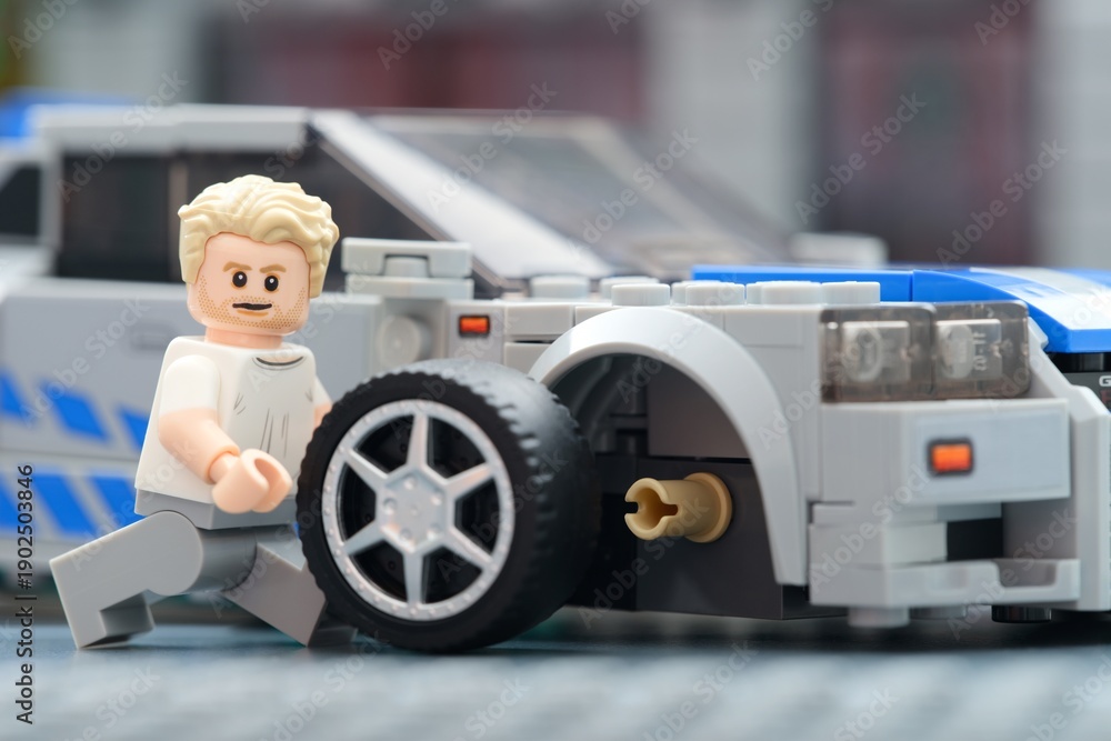 Fototapeta premium Tambov, Russian Federation - August 31, 2025 Lego Brian OConner minifigure changing wheel of his Nissan Skyline GT-R (R34) car. Lego Speed Champions