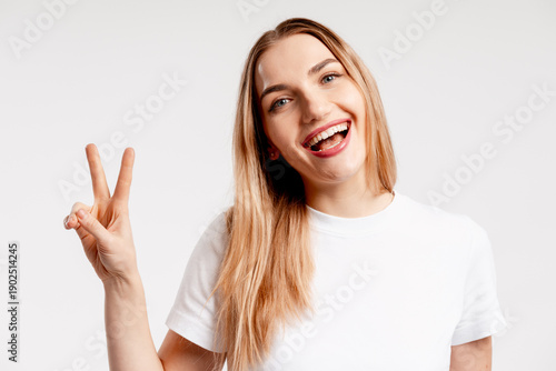 Wallpaper Mural Young woman smiling, showing victory sign, expressing happiness and success Torontodigital.ca