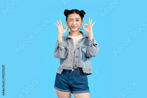 Cuadro en lienzo Young woman winking and making an okay gesture against a vibrant background