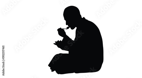 A man eating with a fork captured in a dark silhouette