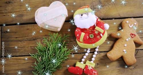 Displaying plush Santa ornament on rustic wood plank with cookie and heart box, copy space
