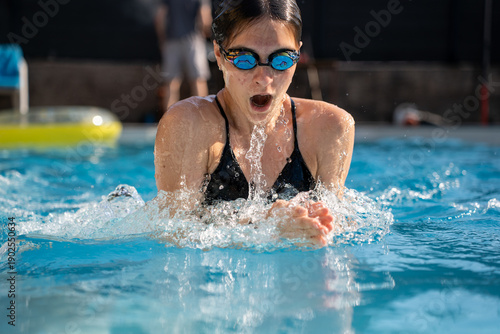 Bild auf Leinwand Girl performing breaststroke in swimming pool, healthy lifestyle activity