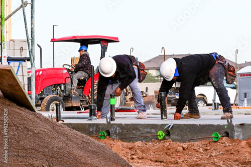Bild auf Leinwand Workers marking layout lines with chalkline on concrete slab for a future wooden