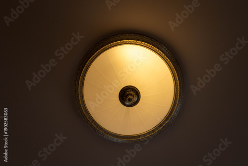 Photos Low angle view of a vintage round ceiling lamp with warm glowing light