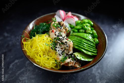 Fresh chicken poke bowl featuring sliced avocado edamame seaweed radish and vibrant vegetables