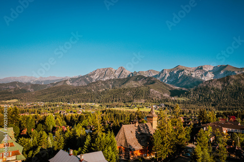 Mountain Village with Traditional Wooden Church and Scenic Peaks at Sunset