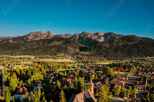 Mountain Village with Traditional Wooden Church and Scenic Peaks at Sunset