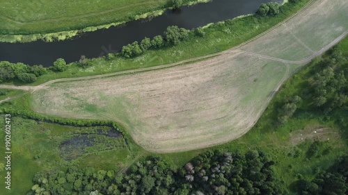 High altitude view of rural fields by the river, slow descent down
