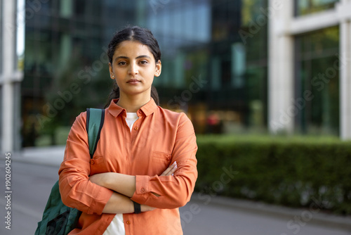 фотографія Young female student standing confidently with arms crossed, wearing casual oran