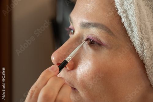 Woman blending eyeshadow with a makeup brush on her face.
Beauty and skincare routine concept. Professional makeup application, cosmetics, self-care, and personal grooming. Close-up portrait.