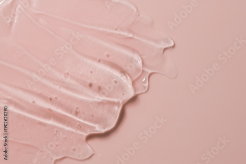 Transparent texture of cosmetic facial gel on a pink peach background. Beauty concept.