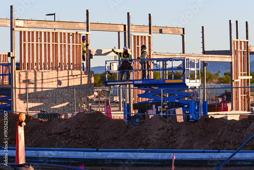 Εκτύπωση καμβά Workers on a scissor lift installing framing at a commercial building site, repr