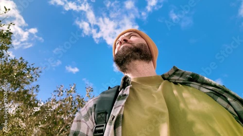 Low angle portrait of man looking up at historic Malta buildings under blue sky.