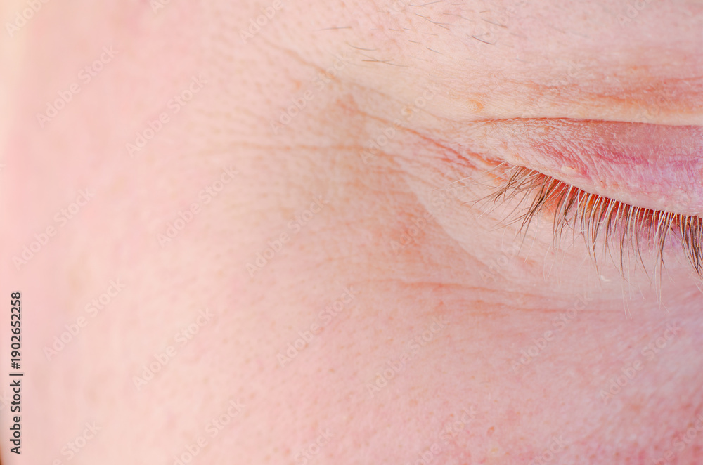 Fototapeta premium Extreme close-up of a closed human eye showing delicate skin texture and eyelashes
