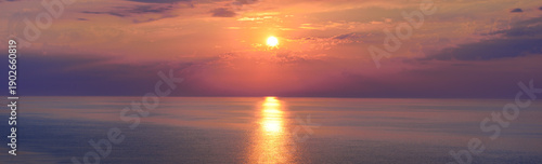 Ocean sunset with dramatic sky and glowing horizon in warm pastel tones, symbol of tranquility