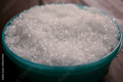 white sugar in a blue bowl placed on a wooden surface