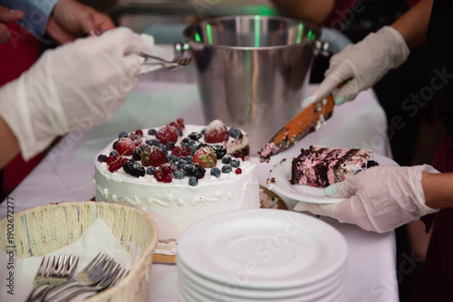 Osoba w rękawiczkach serwuje tort owocowy