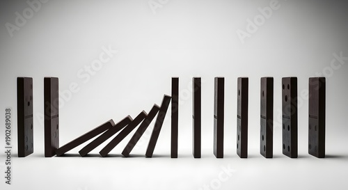Domino effect in motion with black tiles falling in a sequence on a white background.