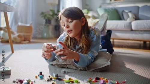 Playful girl building lego on carpet living room closeup. Child creative game