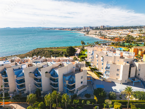Aerial panoramic view of Coastal apartments overlooking Mediterranean Sea in sunny resort town of Cabo Roig, Costa Blanca, Province of Alicante. Spain