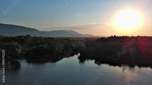 Lake with clear water and stone shore in spruce forest with fir trees against a daytime sky