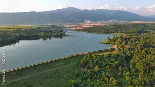 Lake with clear water and stone shore in spruce forest with fir trees against a daytime sky