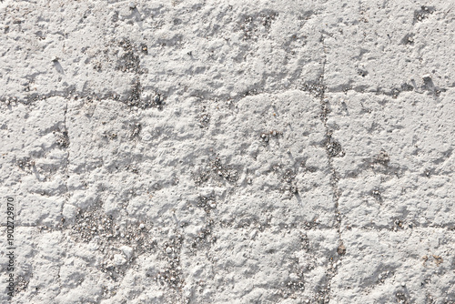 White concrete wall texture background. Rough painted plaster surface closeup. Light gray masonry pattern with cracks. Urban construction material detail. Neutral abstract backdrop.